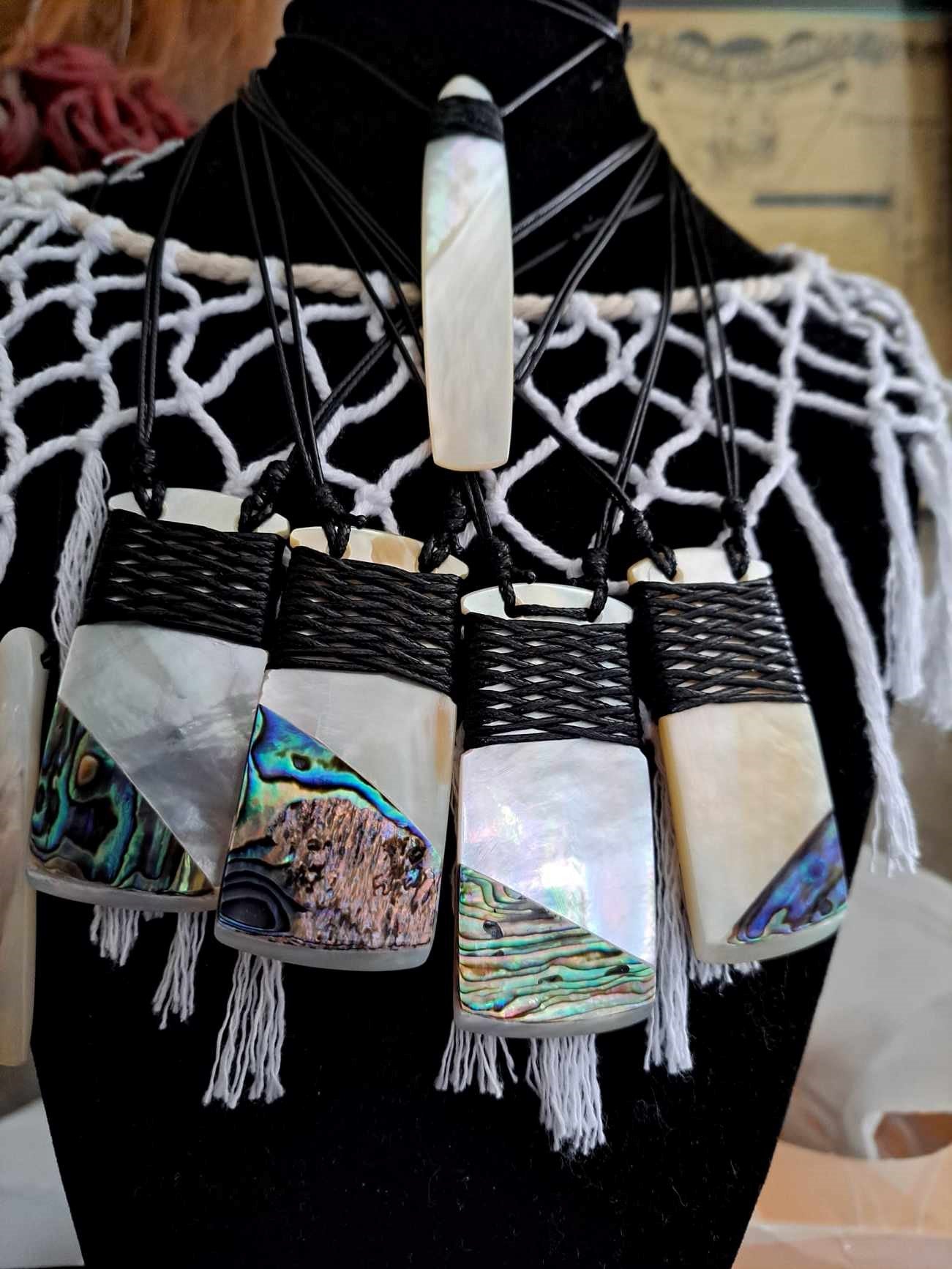 Necklace with abalone shell and black cord on a mannequin.